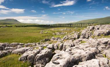 A-train-crossing-Ribblehead-Viaduct-in-the-Yorkshire-Dales-on-a-sunny-day-shot-from-the-limestone-pavement