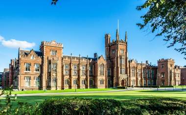 The-Queens-University-of-Belfast-with-a-grass-lawn-tree-branches-and-a-hedge-in-sunset-light